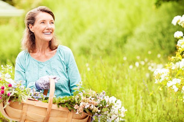 A woman is holding a basket of flowers in a field.