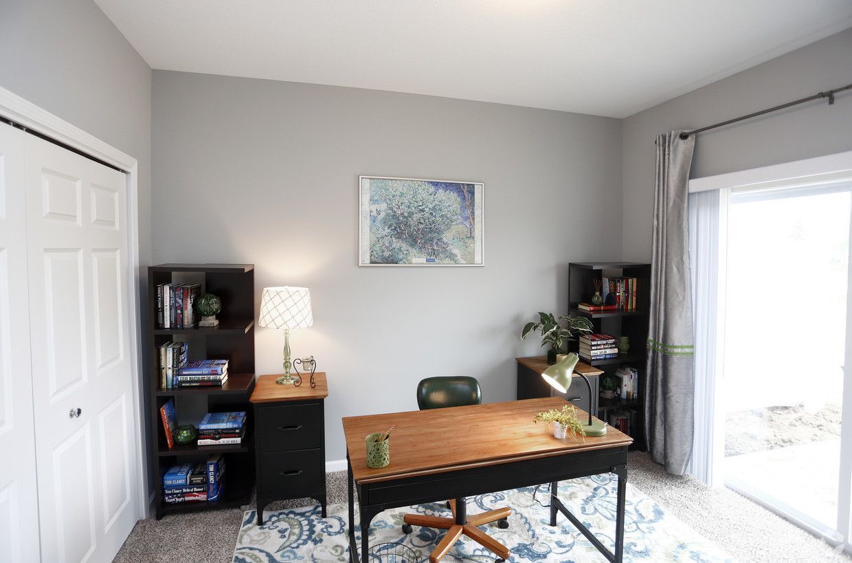 A home office with a desk , chair , lamp and bookshelf.