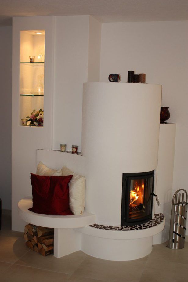 Modernes Wohnzimmer mit weißem, geschwungenem Kamin, brennendem Feuer und eingebautem Regal.