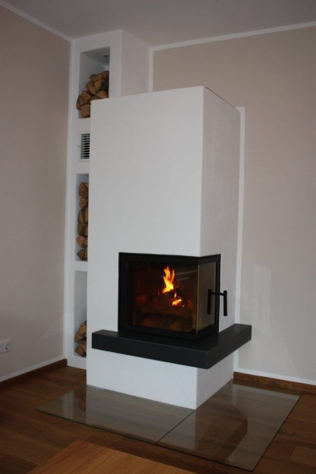 Moderner weißer Kamin mit Glasfront in einem beigen Raum mit Holzboden