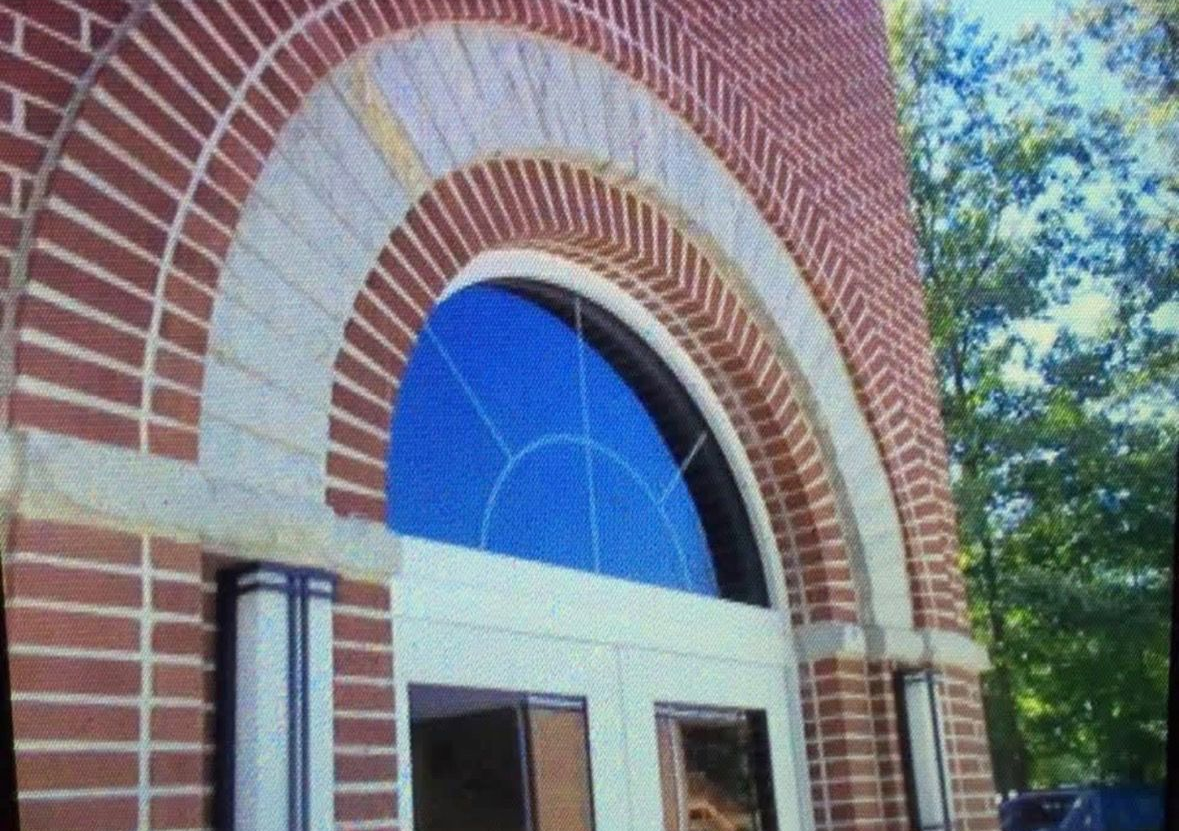 Brick building entrance with arched blue-tinted window and red-and-white brick trim