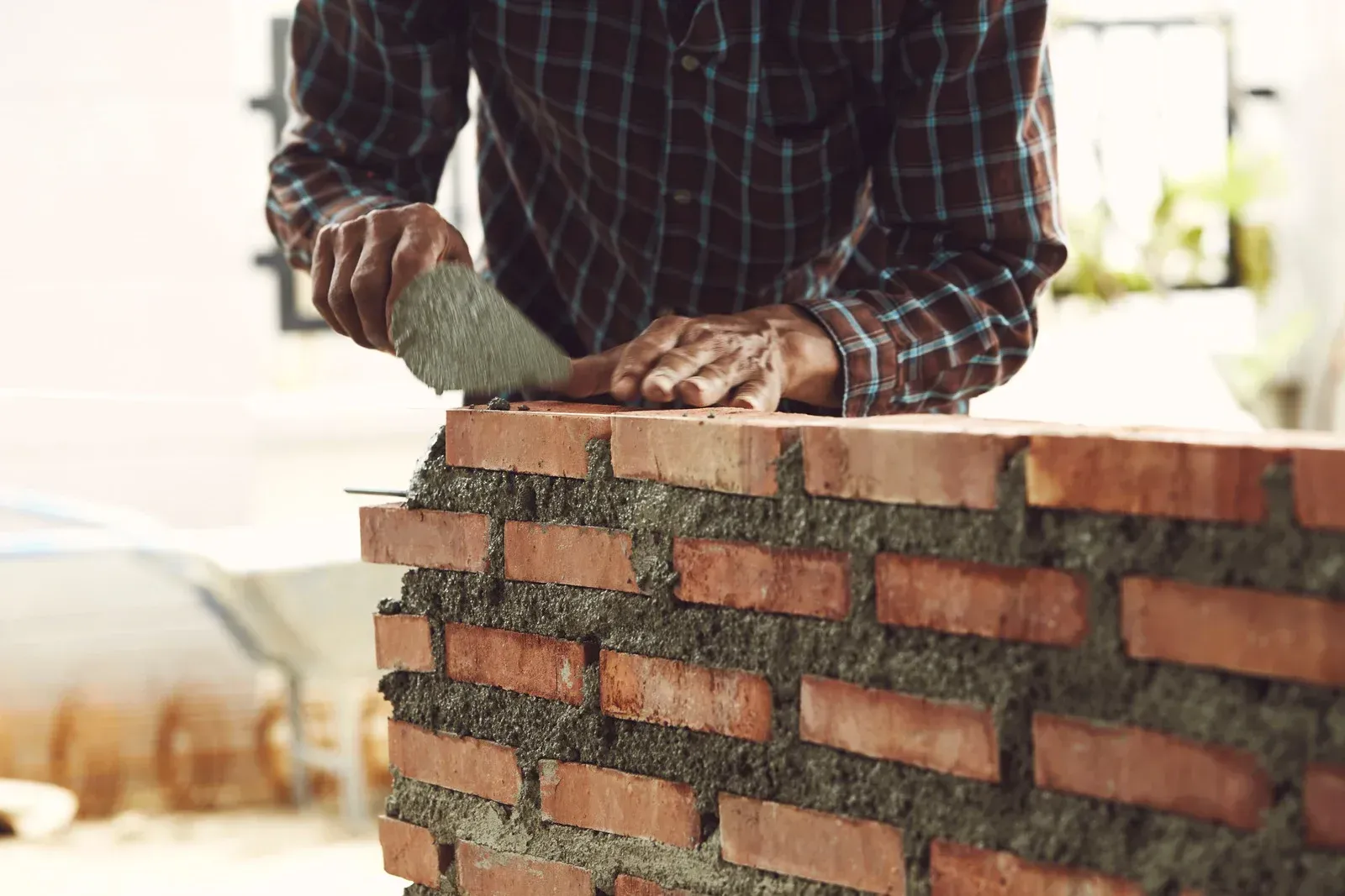 Bricklayer spreading mortar on a brick wall under construction