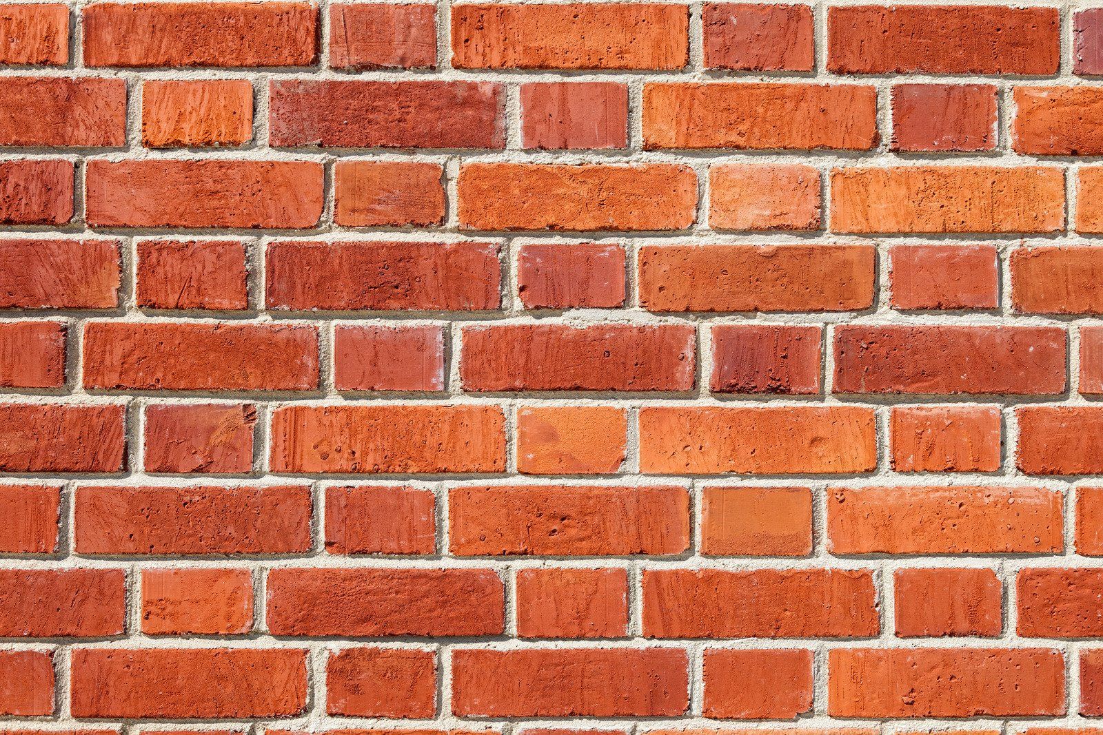 Red brick wall with white mortar lines, evenly laid in a repeating pattern.