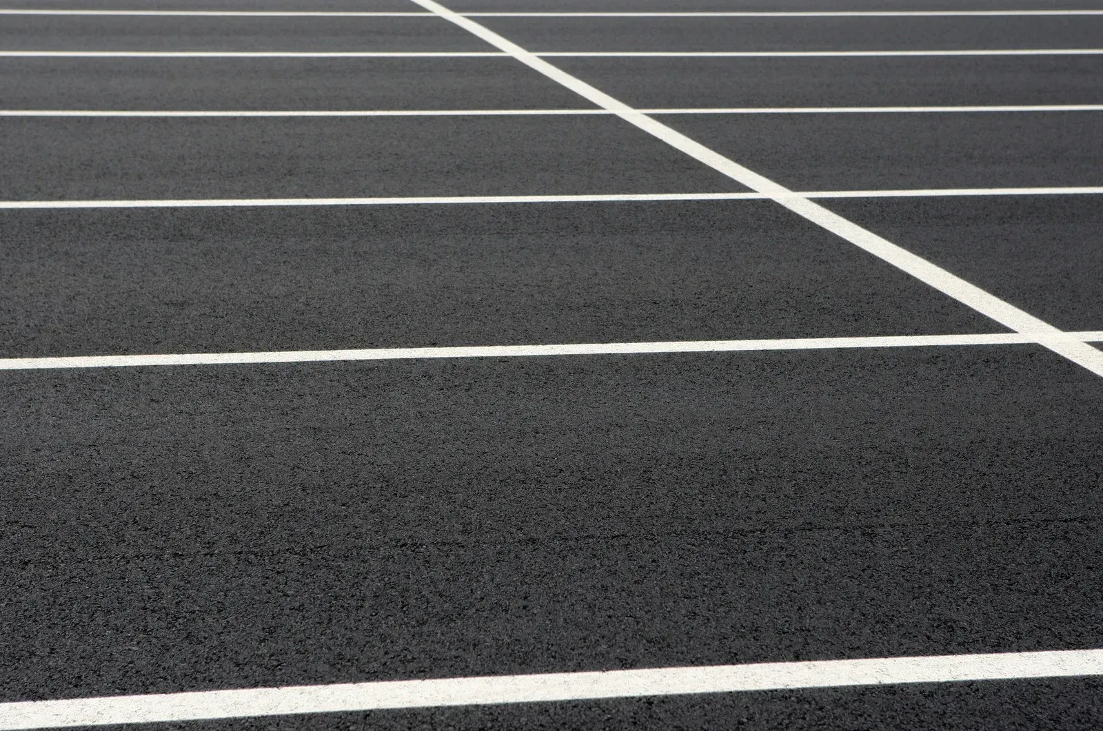Empty asphalt parking lot with white painted parking lines.