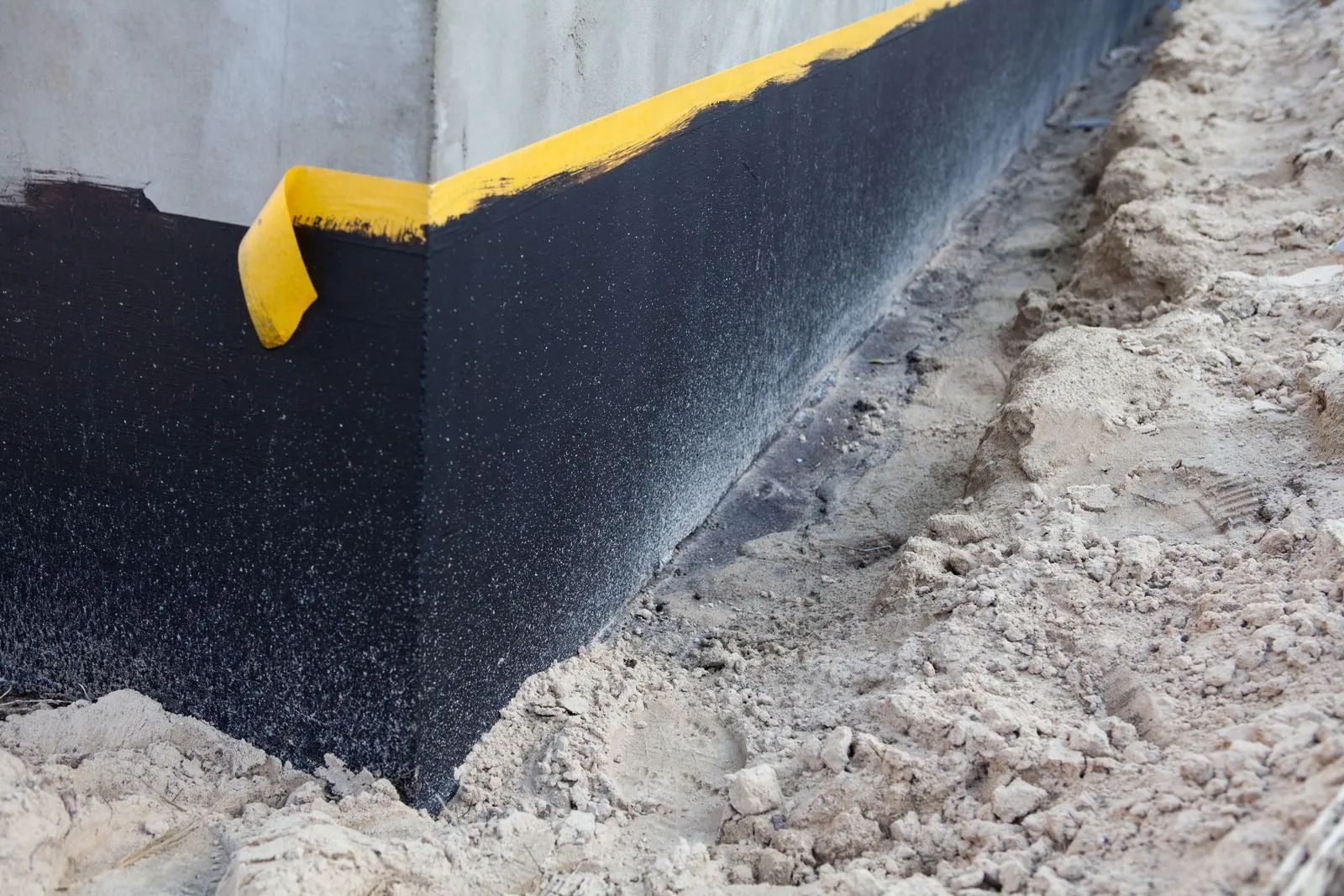 Black and yellow curb edge beside a rough dirt or gravel surface