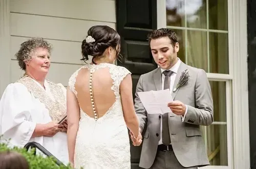 Wedding officiant reading vows to a couple outdoors on a porch