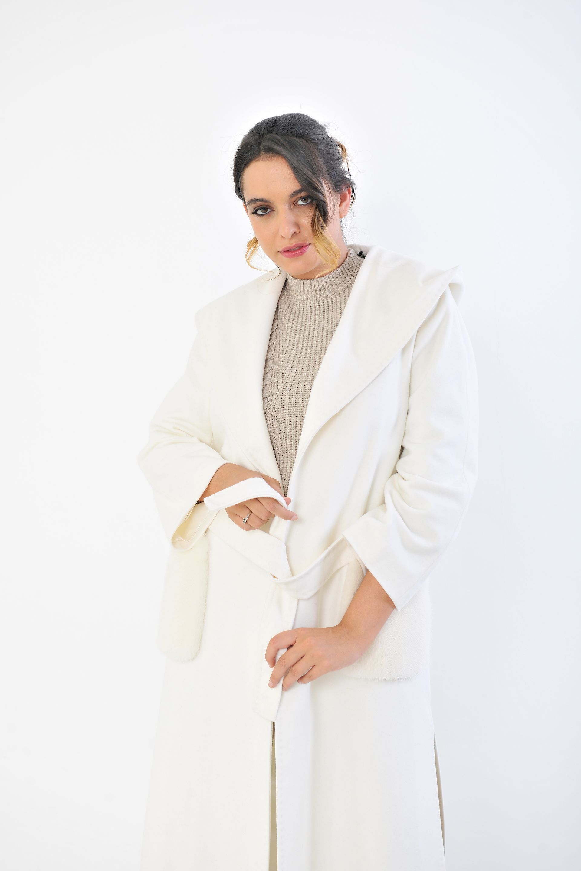 Donna in camice bianco, top beige fantasia, orecchini d'oro. Su sfondo bianco.