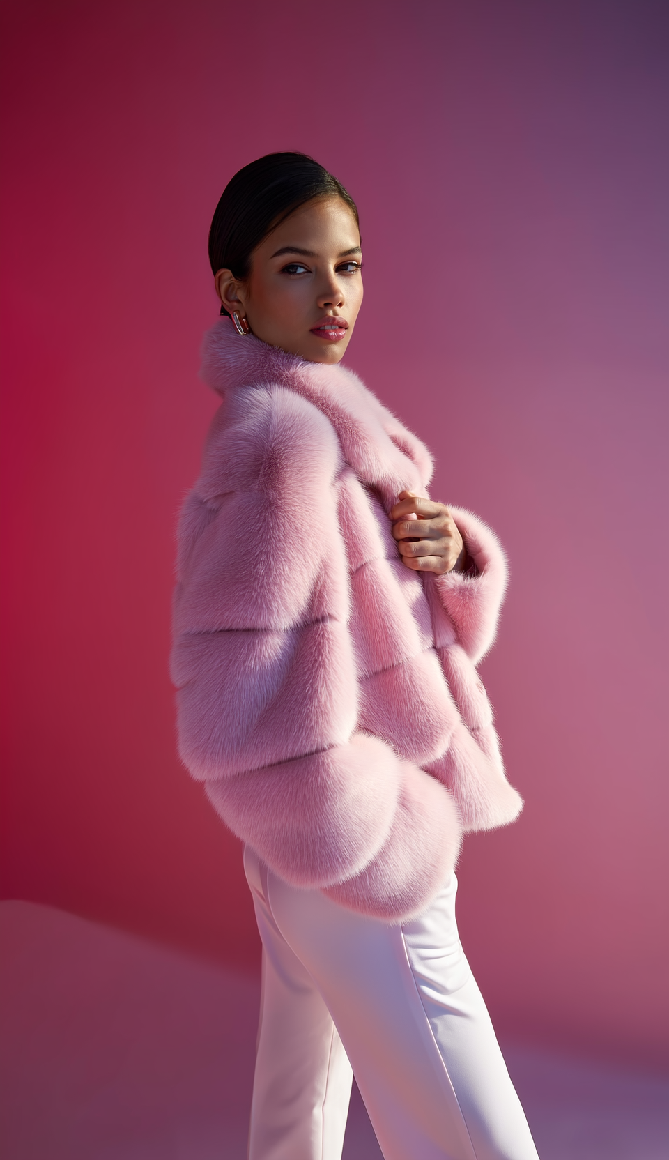 Donna in giacca di pelliccia sintetica rosa, in piedi, su uno sfondo sfumato di rosa.