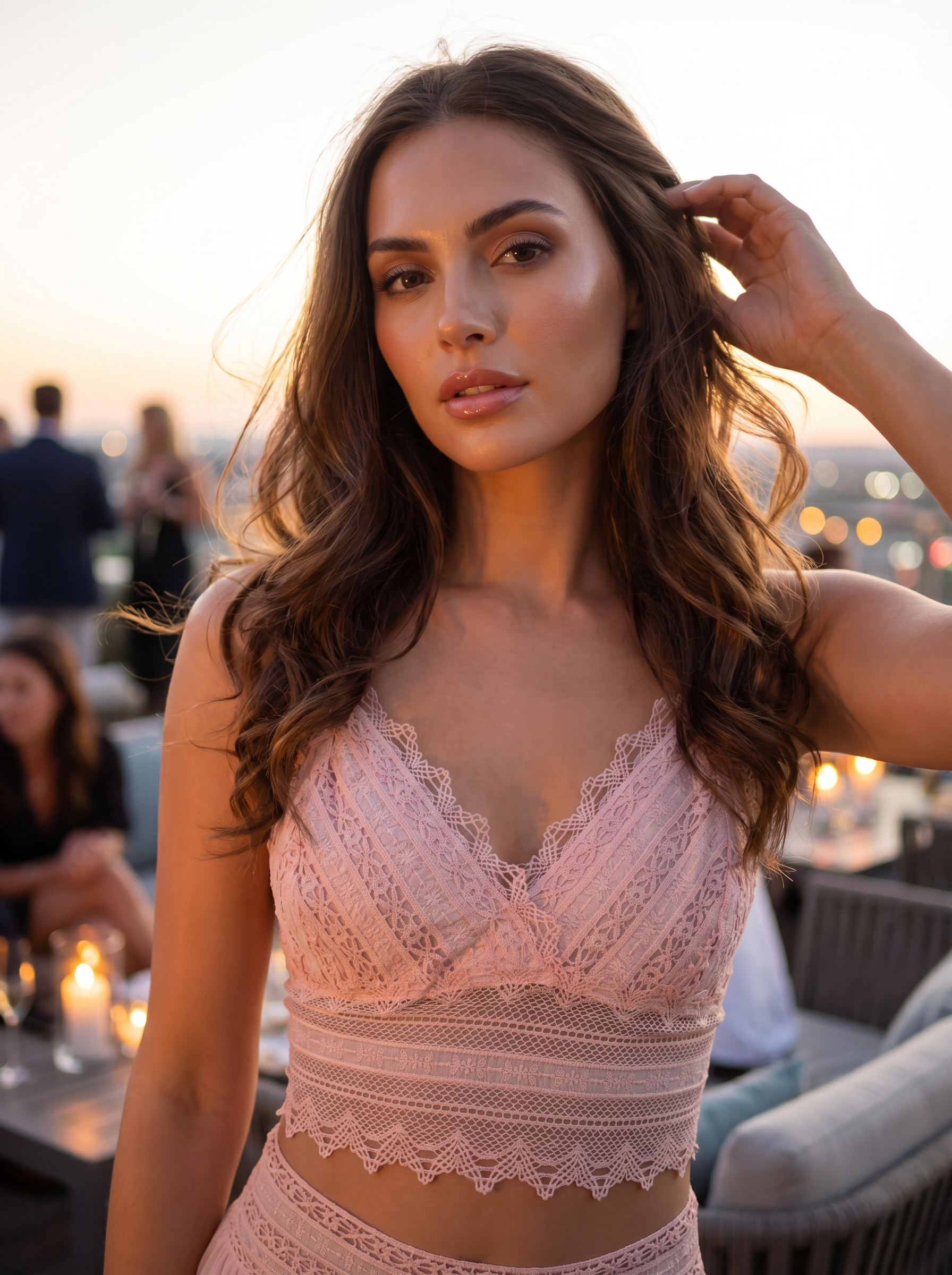 Una donna con un abito di pizzo rosa è in piedi su un tetto al tramonto, con le luci della città sullo sfondo.