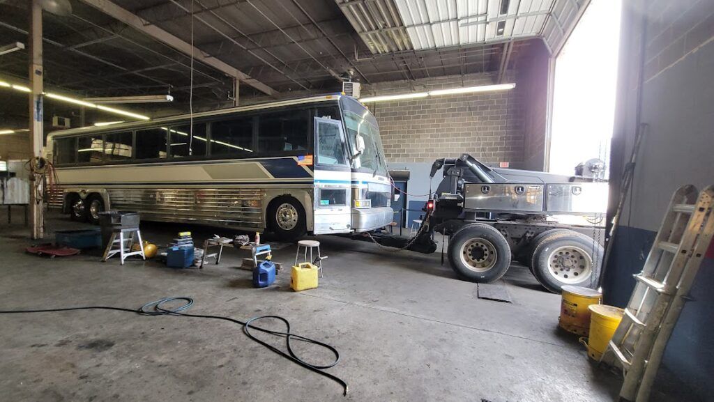 A bus is parked in a garage next to a truck.