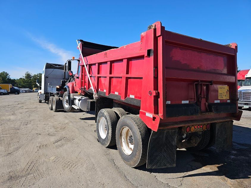 A red dump truck is parked in a dirt lot A red dump truck is parked in a dirt lot
