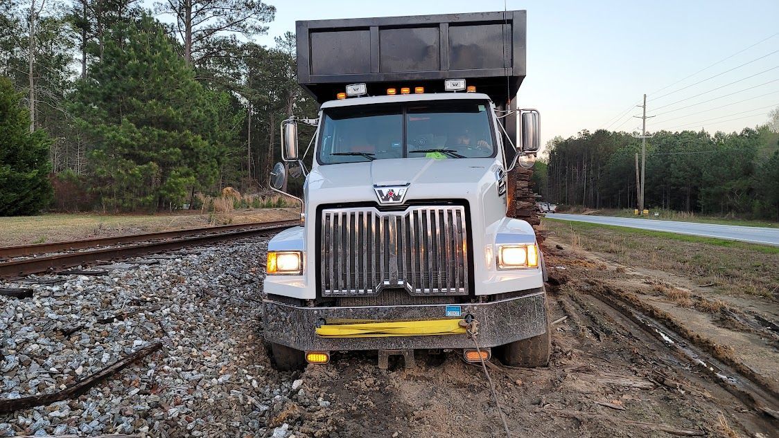 A dump truck is stuck in the mud on the side of the road. A dump truck is stuck in the mud on the side of the road.