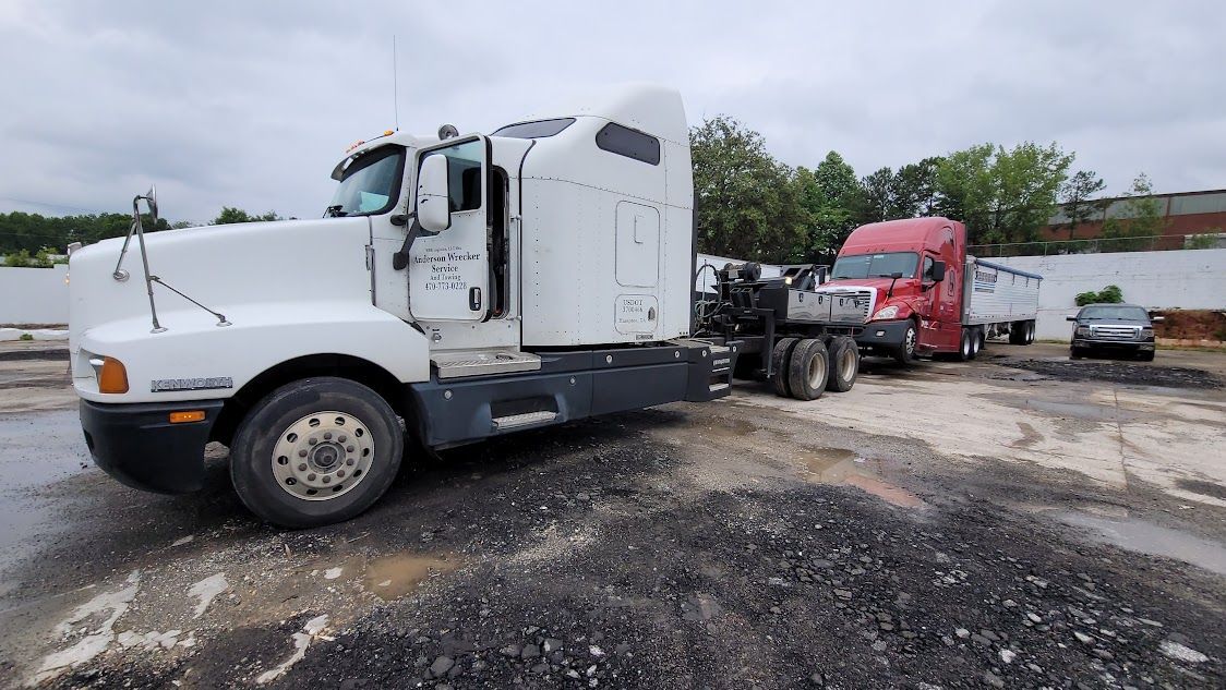 A white semi truck is parked next to a red semi truck in a parking lot. A white semi truck is parked next to a red semi truck in a parking lot.