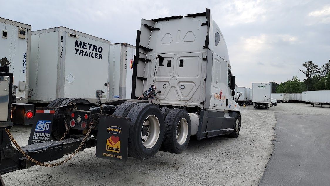 A semi truck with a trailer attached to it is parked in a lot. A semi truck with a trailer attached to it is parked in a lot.