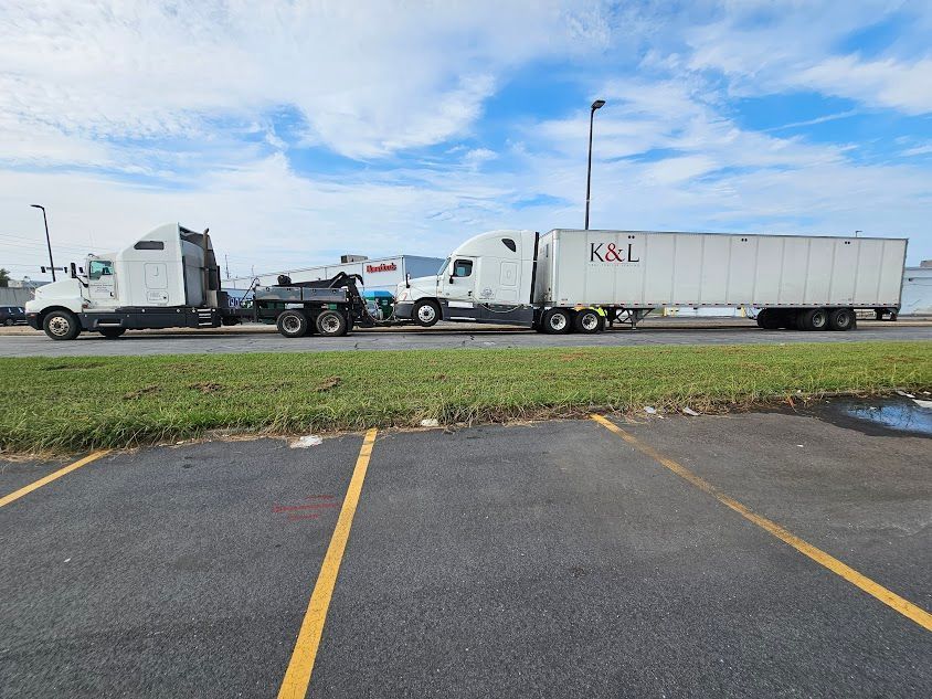 Two big semi trucks are parked next to each other in a parking lot. Two big semi trucks are parked next to each other in a parking lot.