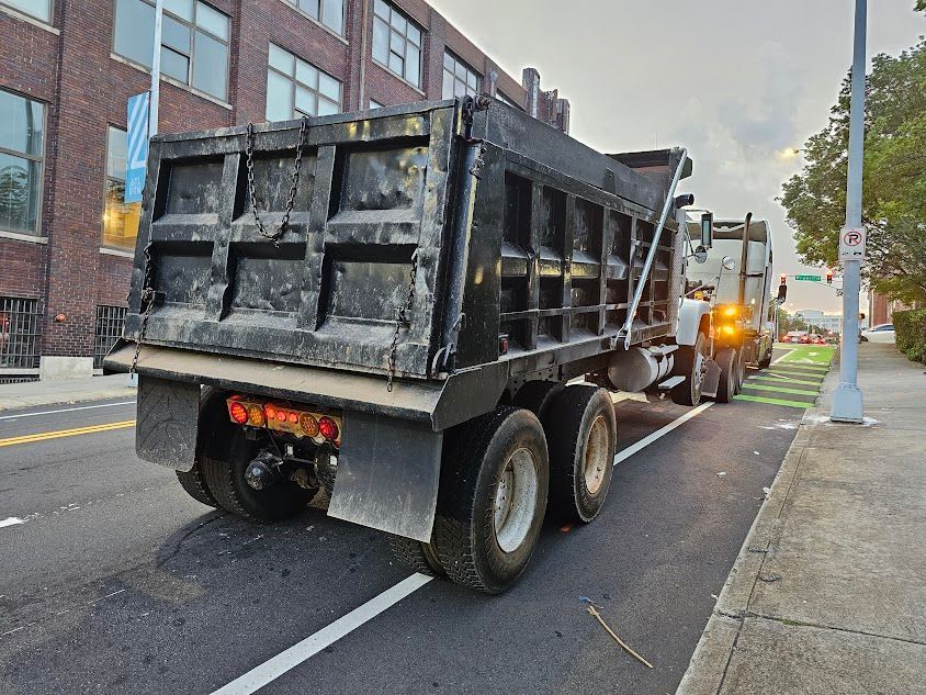 A black dump truck is parked on the side of the road. A black dump truck is parked on the side of the road.