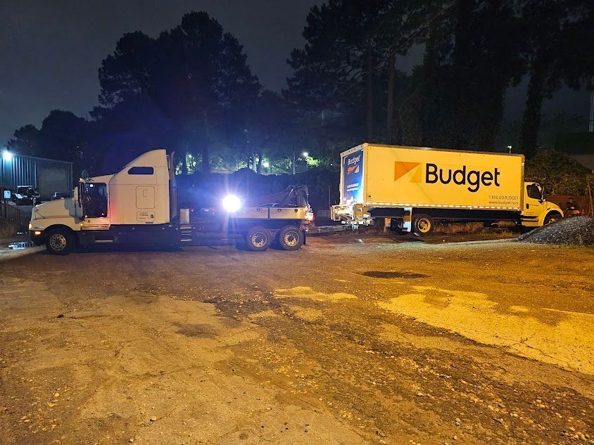 A truck is towing another truck in a parking lot at night. A truck is towing another truck in a parking lot at night.