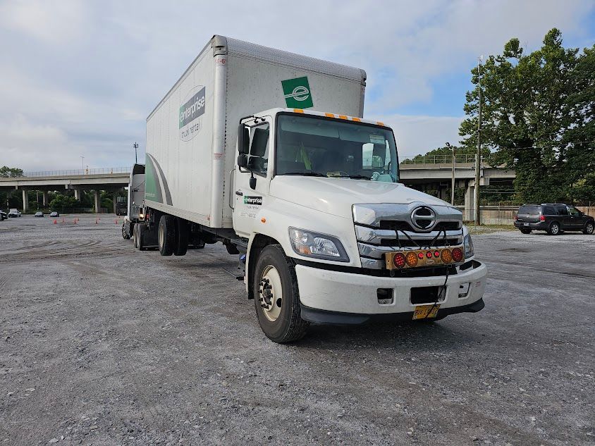A white box truck is parked in a gravel lot. A white box truck is parked in a gravel lot.