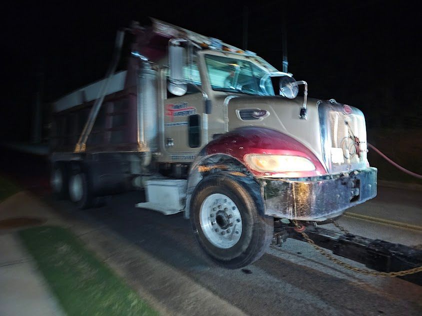 A dump truck is parked on the side of the road at night A dump truck is parked on the side of the road at night