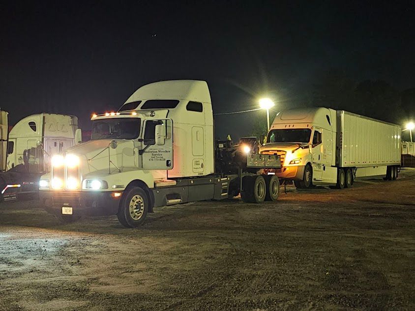 Two semi trucks in a parking lot at night.