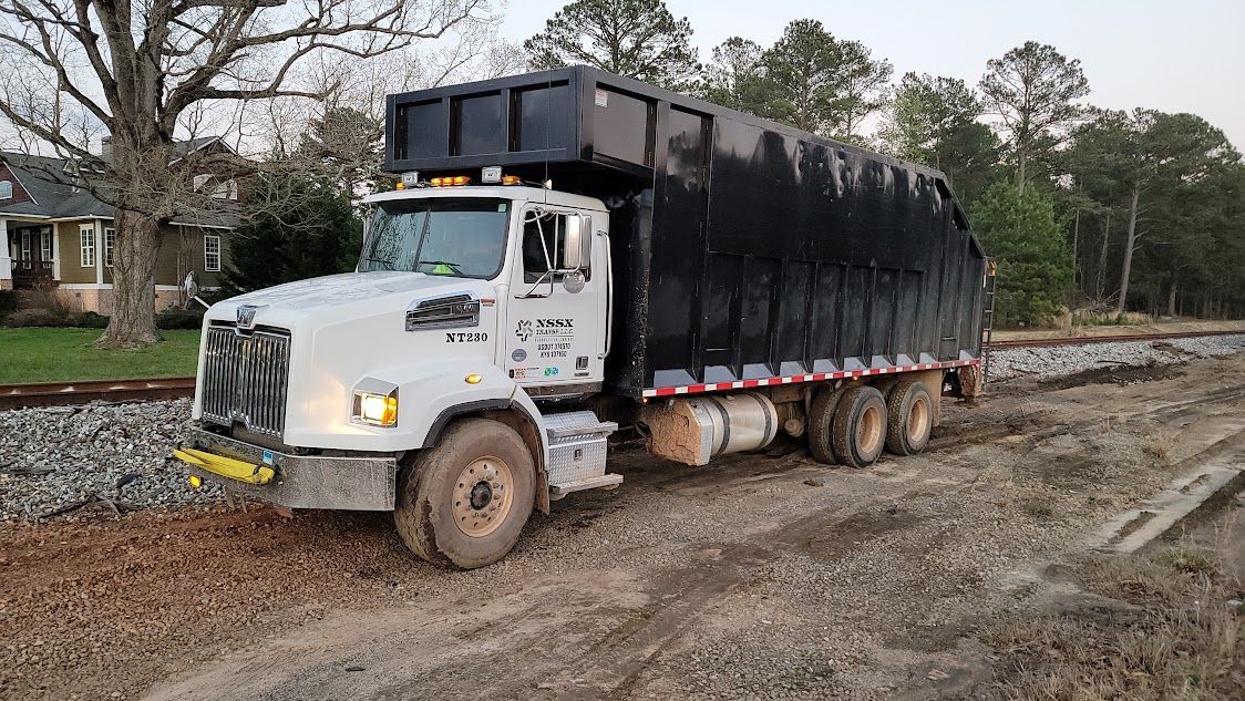 A white dump truck is parked on a dirt road