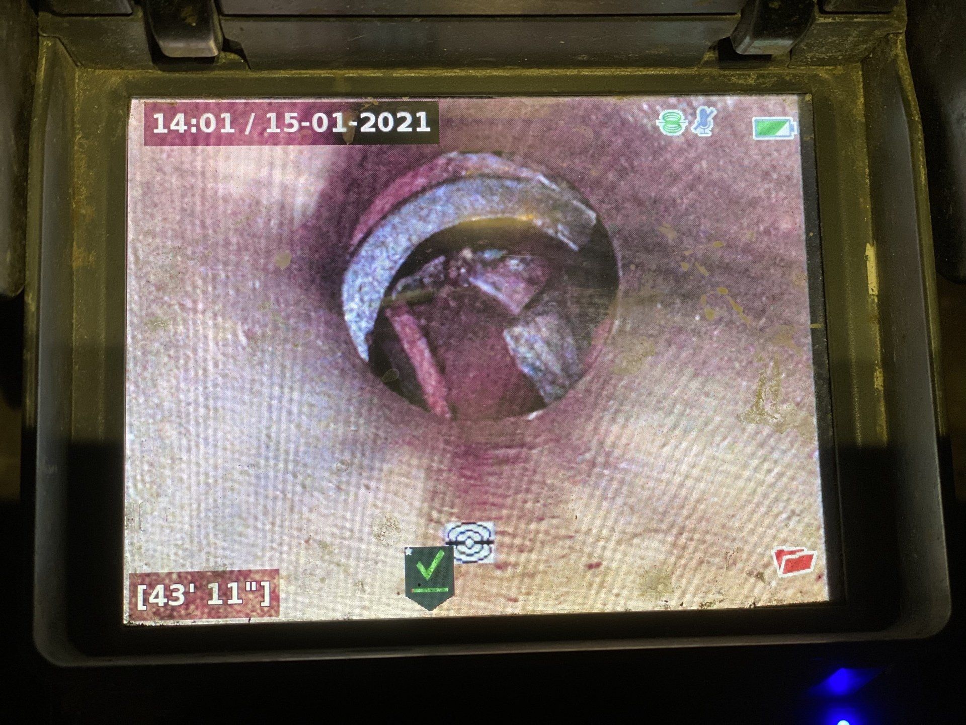 La caméra filme l'intérieur d'une canalisation et montre des débris obstruant l'ouverture. La date et l'heure sont affichées.