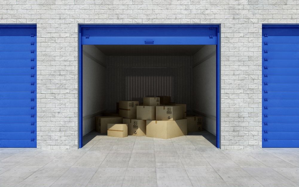 A Stack of Cardboard Boxes in a Garage With Blue Doors — North Coast Storage in North Boambee Valley, NSW