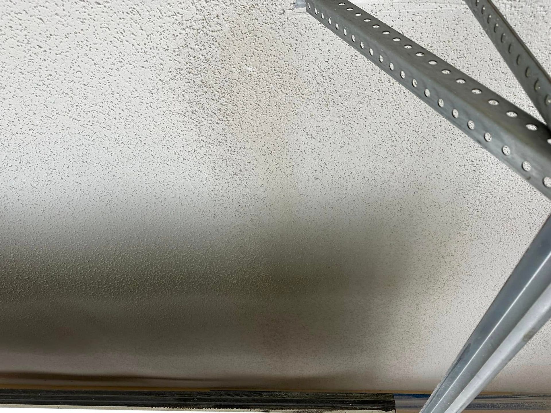 Ceiling with metal garage door tracks and speckled white panels