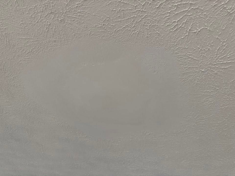 Close-up of a textured white ceiling with a faint gray patch near the center