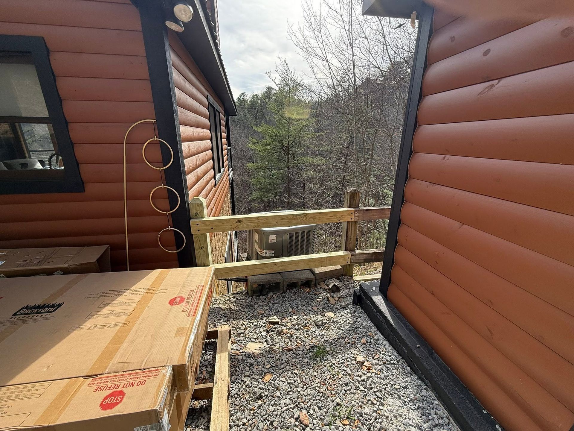 Two log cabins connected by a small wooden deck overlooking a wooded hillside.
