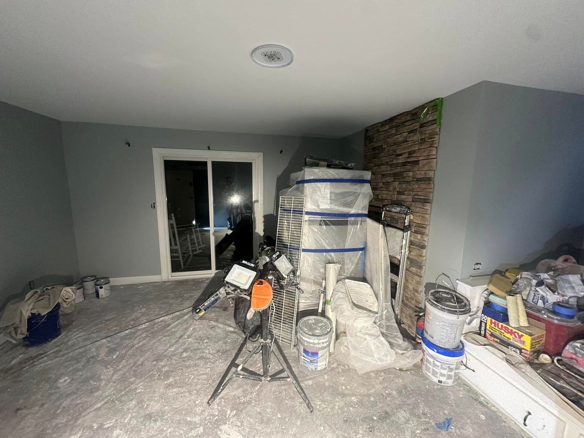Renovated living room with tools, supplies, and stacked materials against a stone accent wall