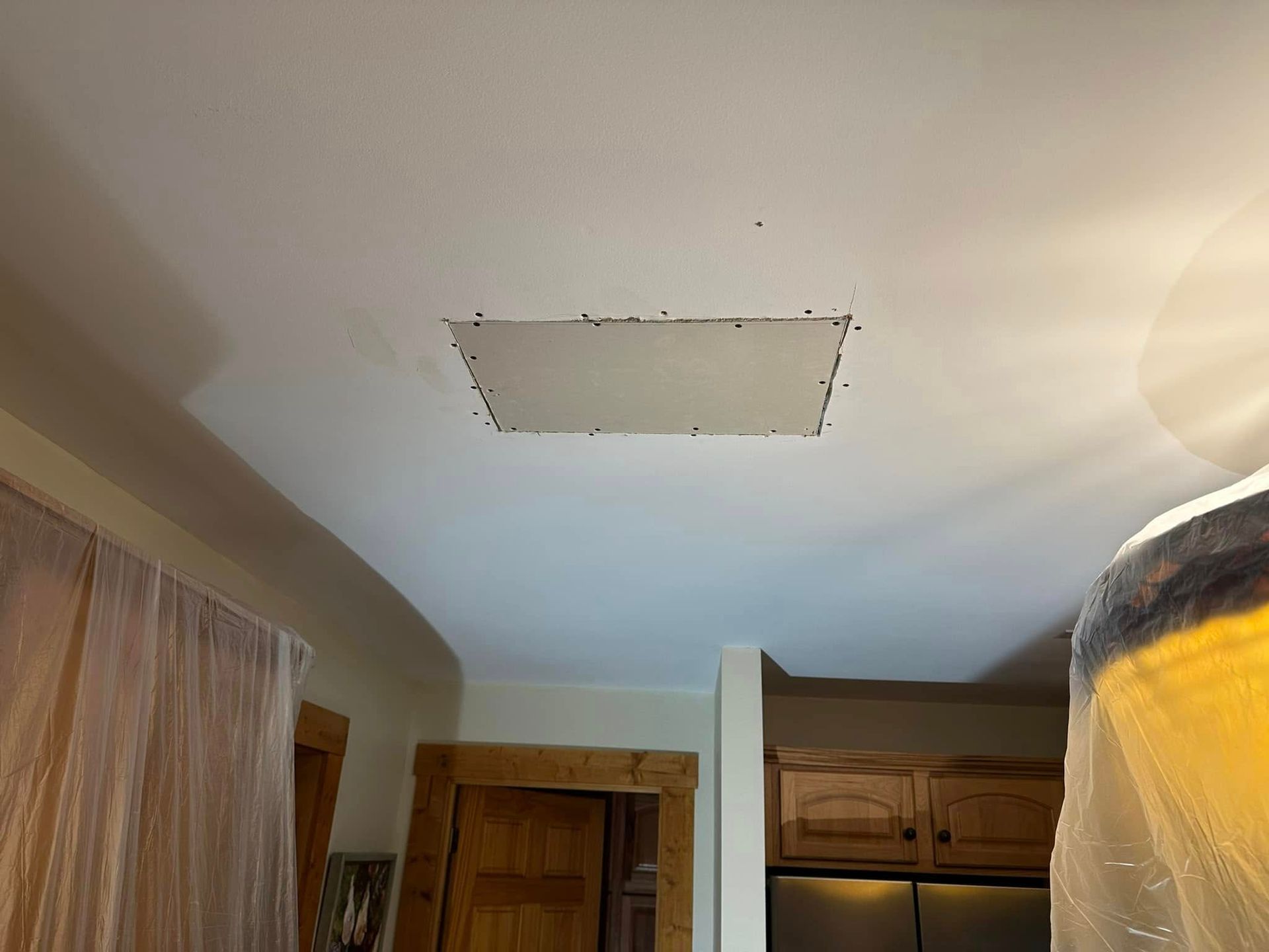 Bedroom ceiling with a square drywall patch and a light fixture on the right