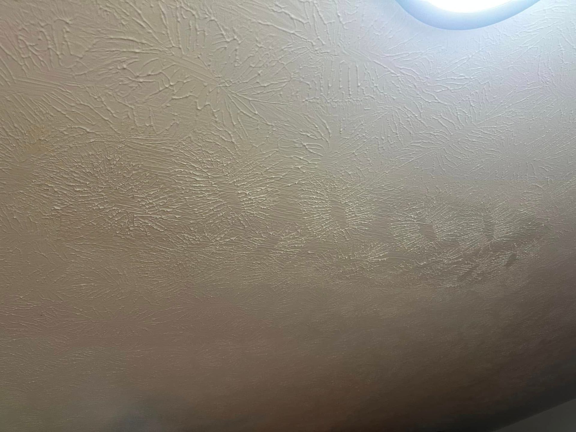 Beige textured ceiling with a bright round light in the upper right corner.