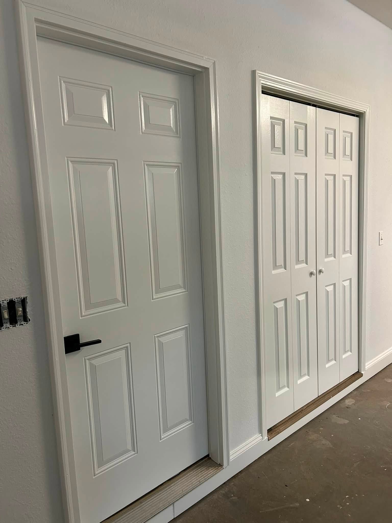 Two white interior doors in a hallway with gray walls and decorative trim.