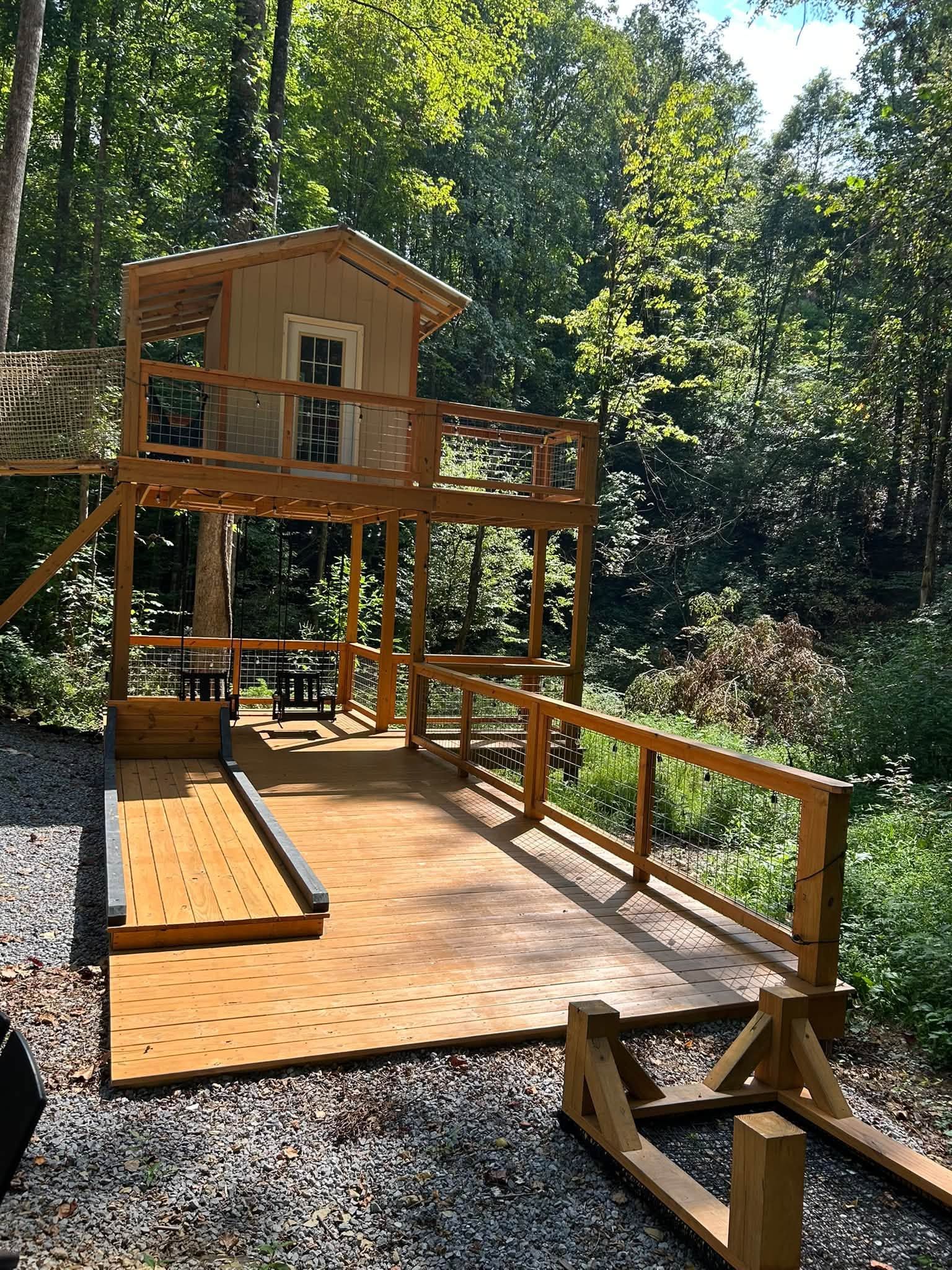 Wooden treehouse deck and ramp in a sunny wooded backyard