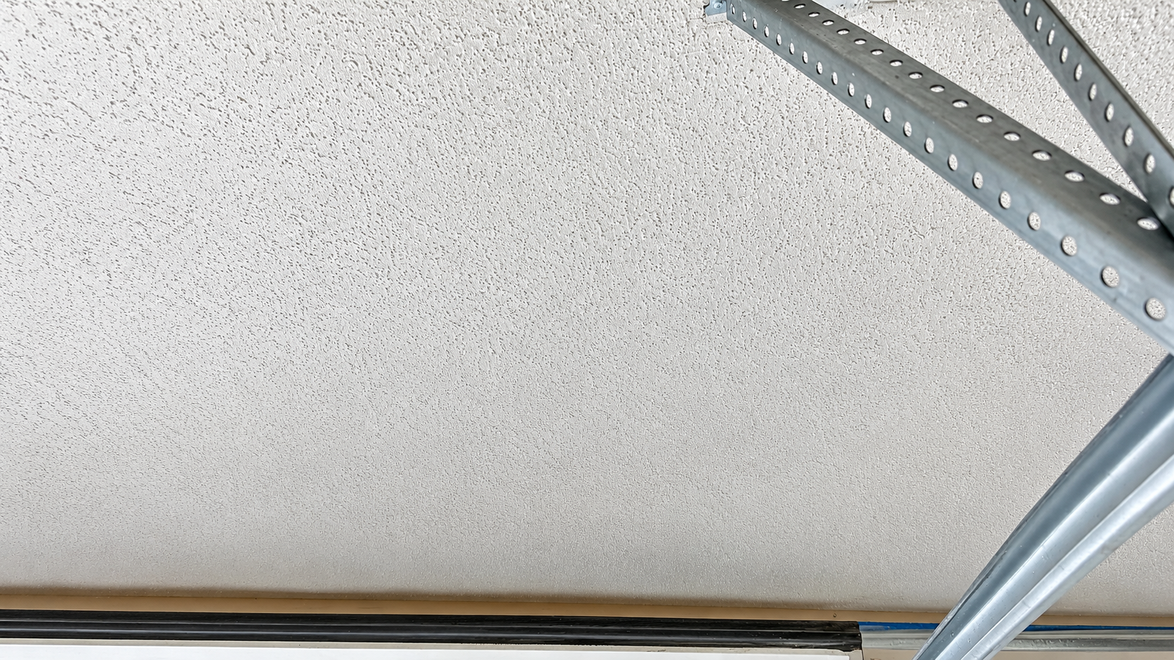 Ceiling with a metal garage door track and support bracket in the corner