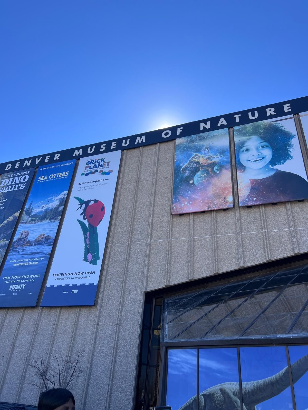 Denver Museum of Nature & Science exterior with banners against a bright blue sky