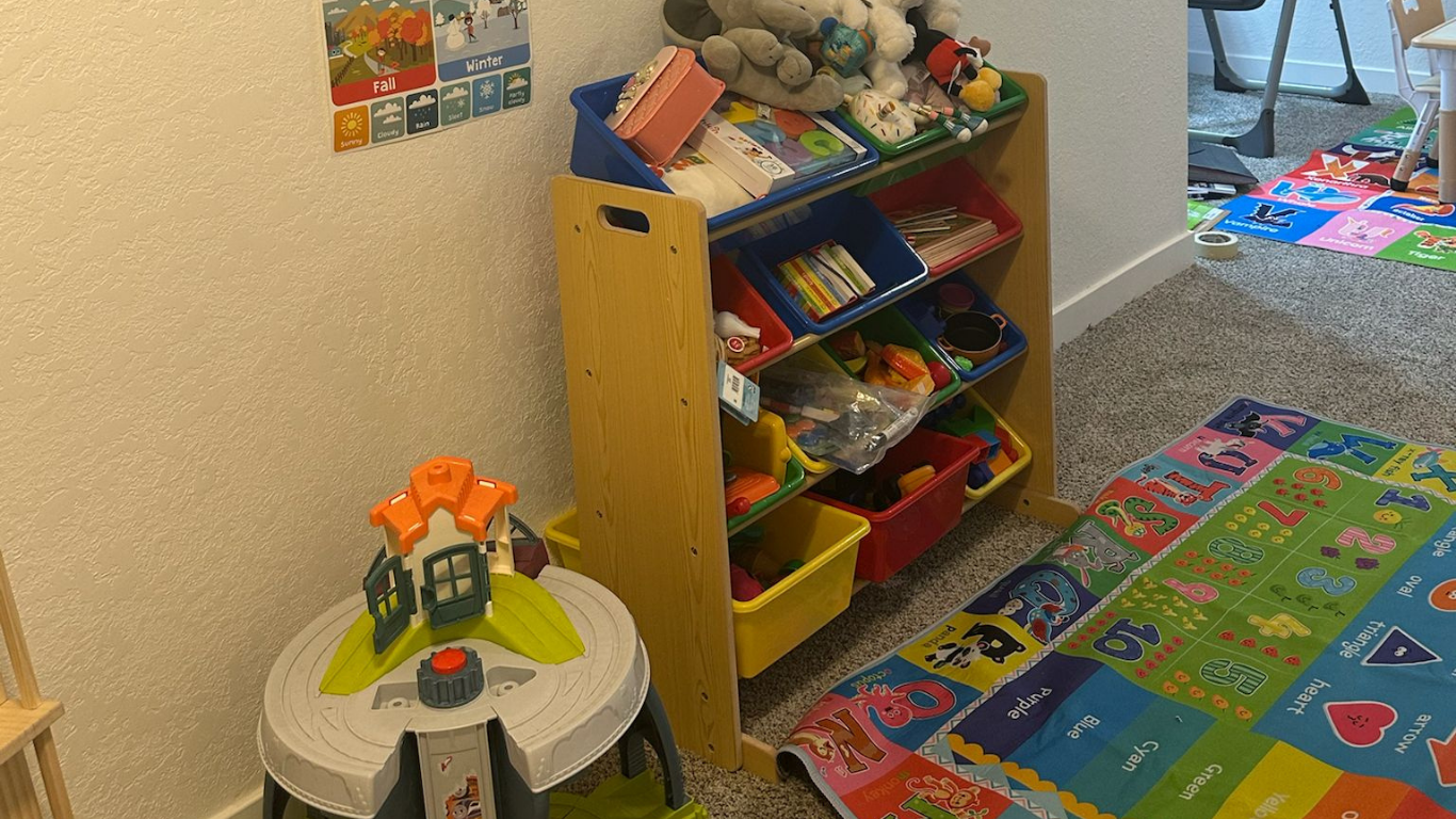Children’s play corner with toy shelf, stuffed animals, activity table, and colorful floor mats
