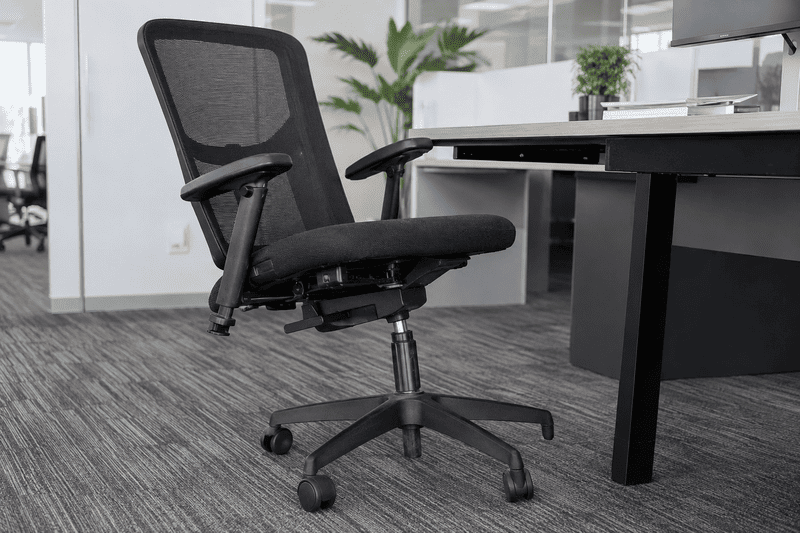 Black office chair beside a white desk in a modern office with carpeted floor