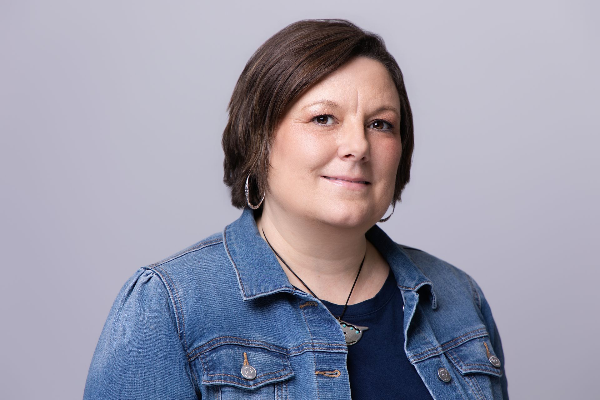 Portrait of a person in a denim jacket against a light gray background