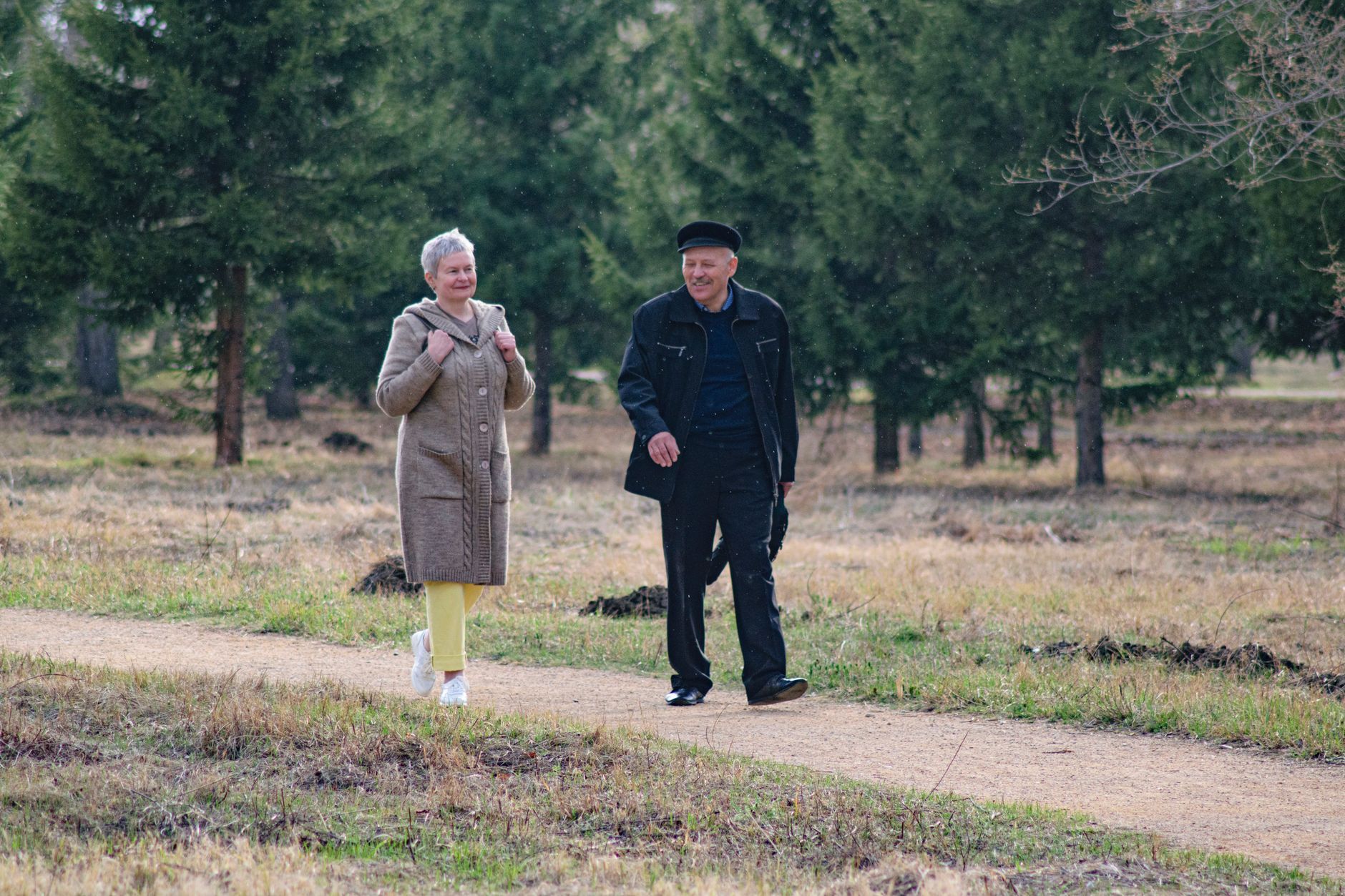 Older couple smiling as they walk together on a park trail