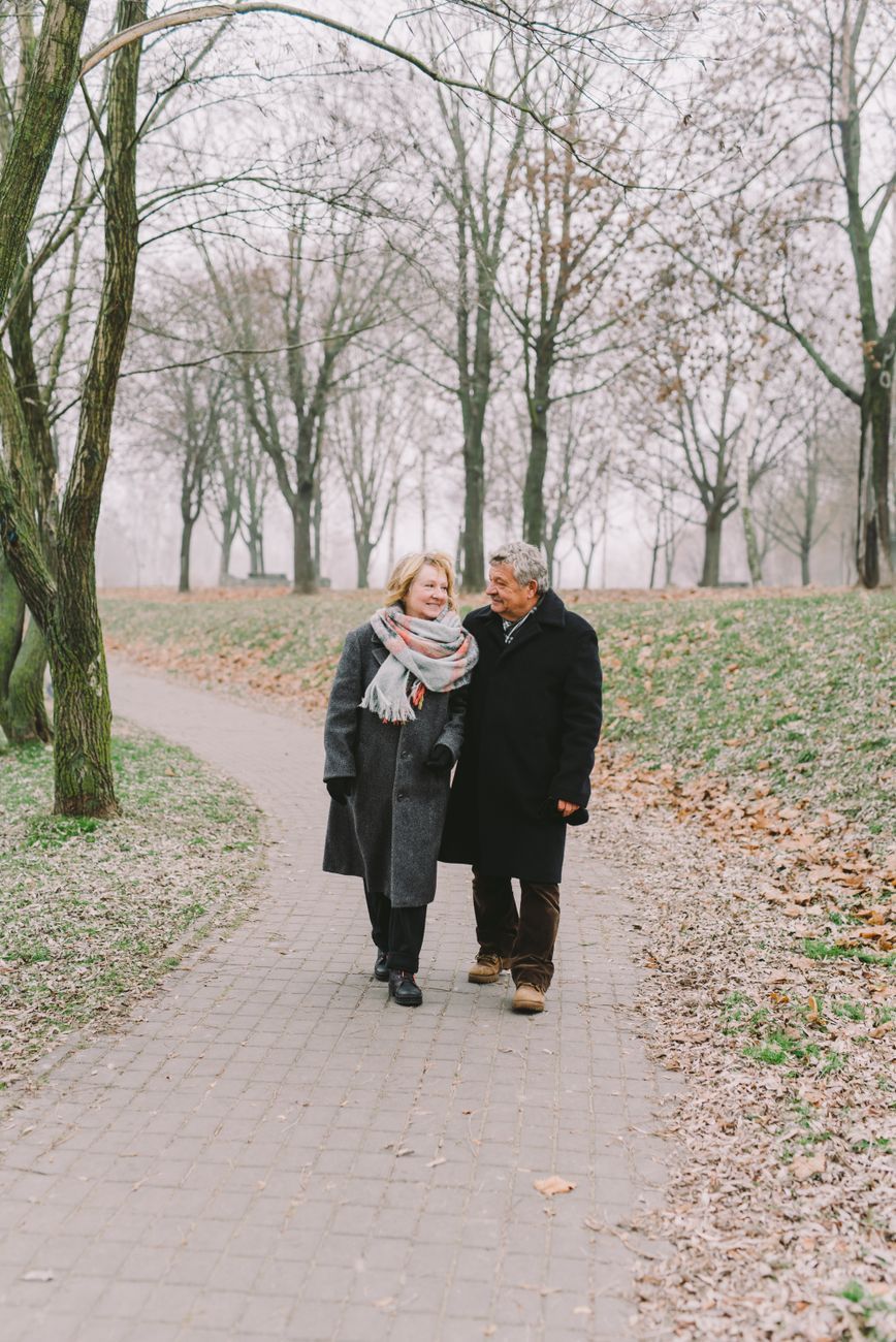Older couple walking together under autumn trees