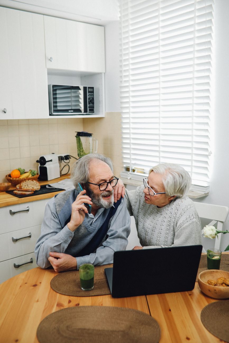 Older couple at the kitchen table with a laptop