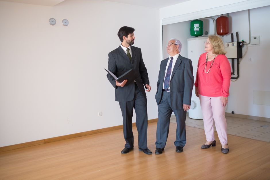 Older couple touring an empty home with a representative