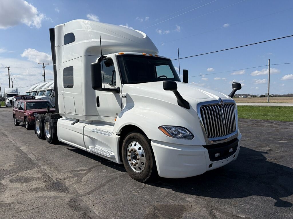 White semi-truck with flatbed trailer parked on a roadside under a blue sky