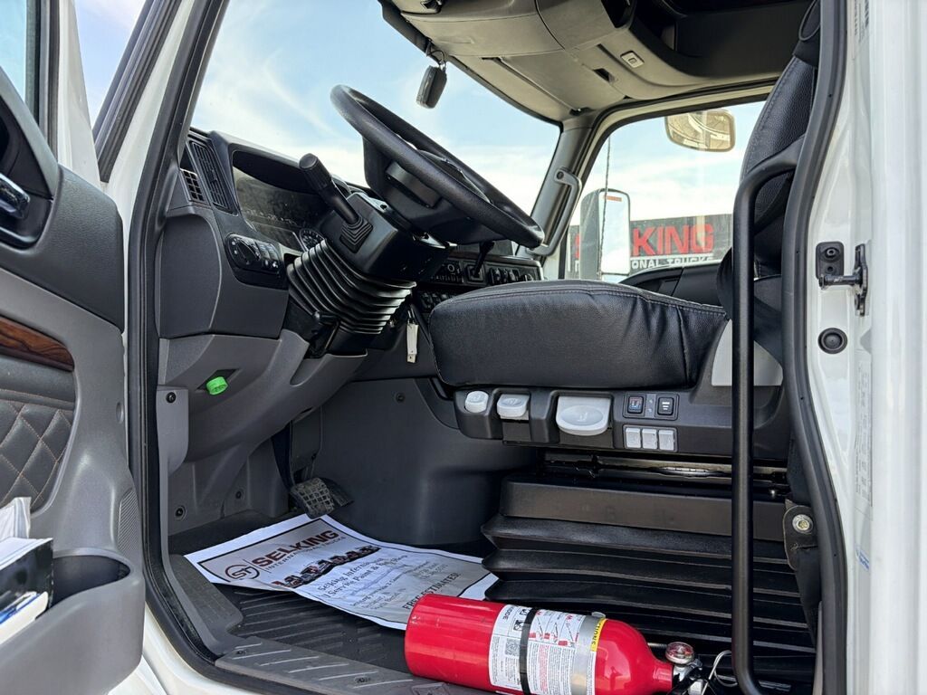 Open truck cab with papers on the floor and a red fire extinguisher by the passenger seat.