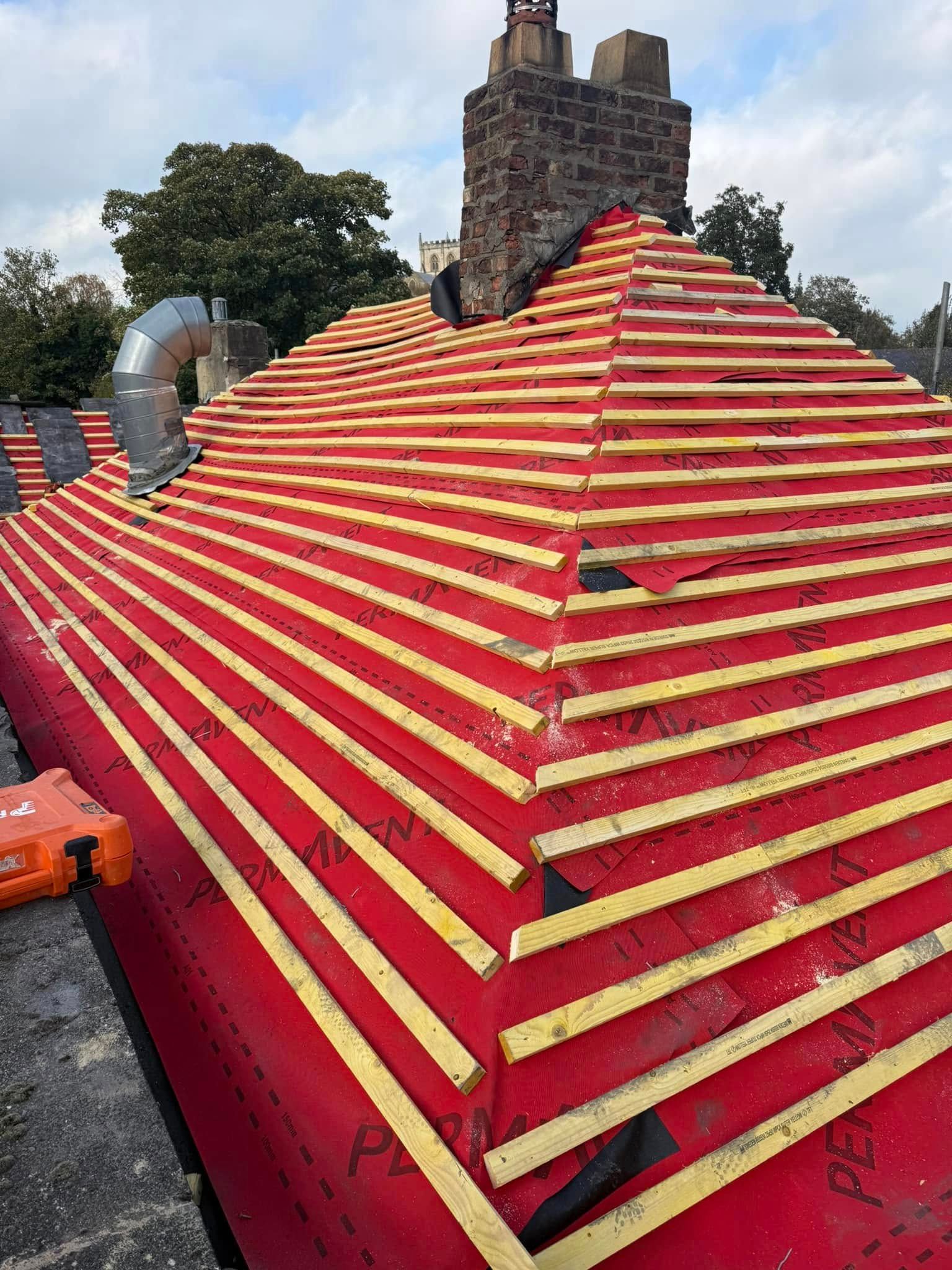 A red and yellow roof is being built on a house.