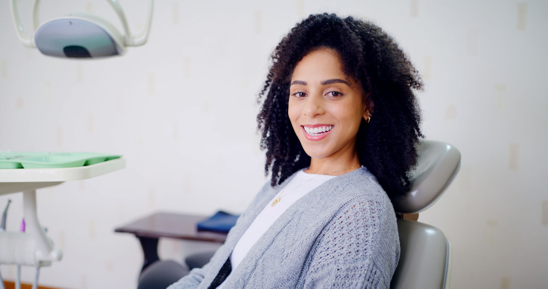 Person sitting in a dental chair, smiling during a routine checkup.