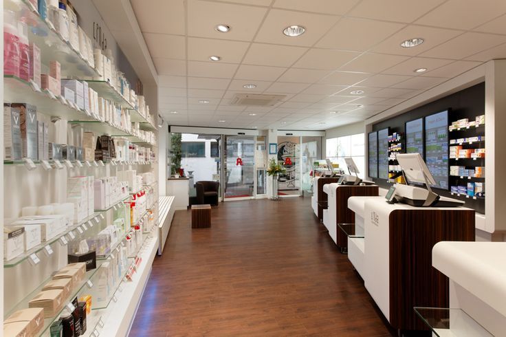 Innenansicht einer gut beleuchteten Apotheke mit Produkten in Regalen und modernen Kassentheken.