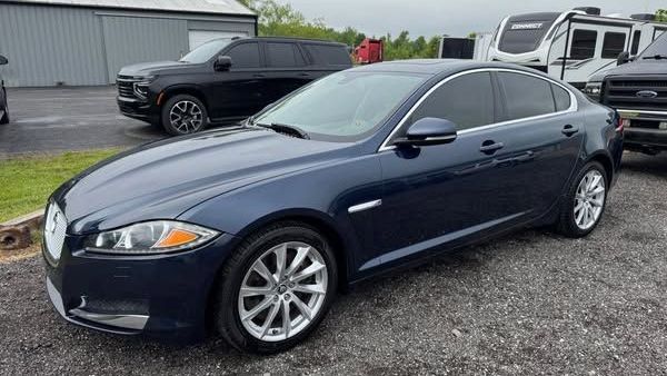 Blue sedan parked on gravel lot in front of industrial buildings